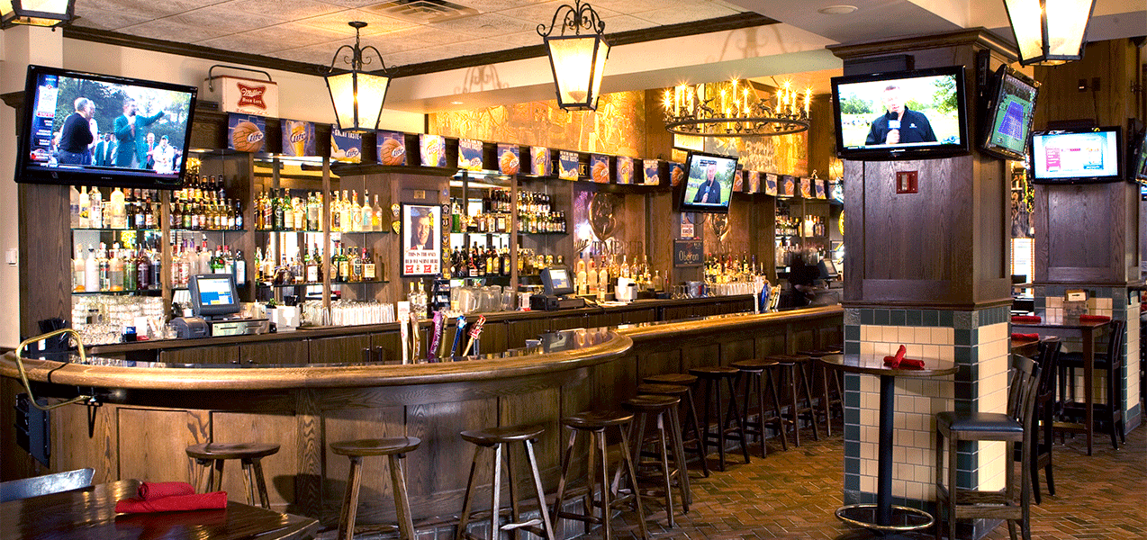 Long wooden bar, tables, chairs and television as built by Tri-North Builders inside the Miller Time Pub.